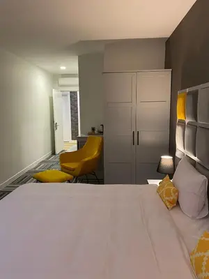 a bedroom with a large white bed and a yellow chair at Continent Luxury Suites Sakarya in Sakarya