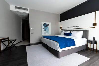 a bedroom with a large bed with a blue blanket at Hotel Bonvie in Sakarya