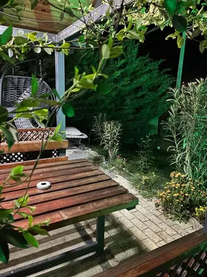 a wooden bench sitting in a garden with a table at Golden Hour Apartment بورصة شقة مريحة Bursa Nilufer مَنْظَرٌ جَمِيلٌ in Nilüfer