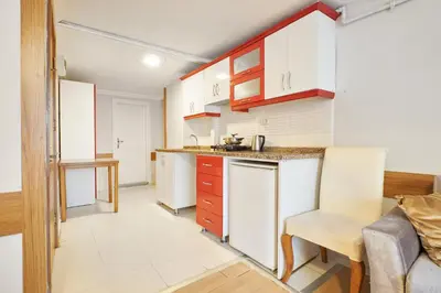 a kitchen with white cabinets and a table and a chair at Central Suites Taksim in Istanbul