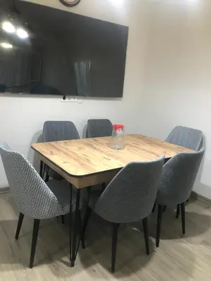 a wooden table with chairs and a television on a wall at Hakan’s apartment in Istanbul