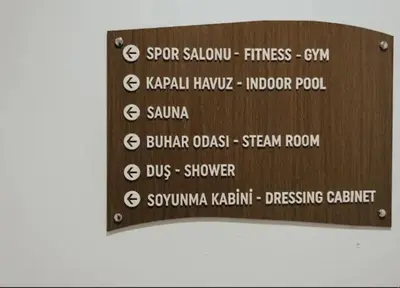 a wooden sign with the names of different restaurants at Cosy Studio Flat -One Room in a new residence near Taksim in Istanbul