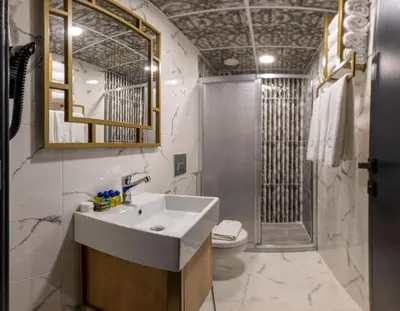 a bathroom with a sink and a toilet and a mirror at Fly And Stay Airport Hotel in Istanbul