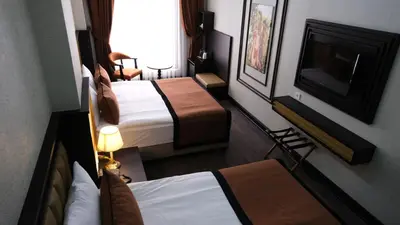 a hotel room with two beds and a flat screen tv at Dimen Hotel in Bursa