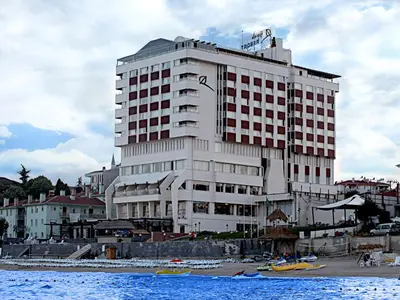 a large white building on the beach with boats in the water at İğneada Resort Hotel & SPA in Igneada