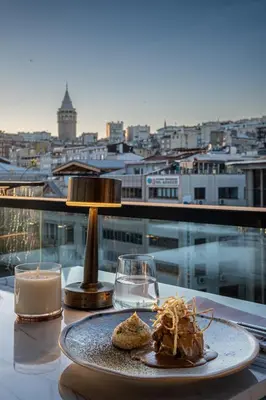 a plate of food on a table with a view of a city at Root Hotel Karaköy Bosphorus in Istanbul