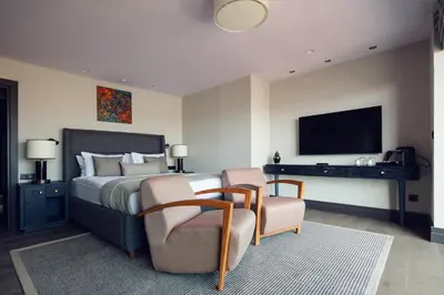 a bedroom with a bed and two chairs and a television at Root Hotel Karaköy Bosphorus in Istanbul
