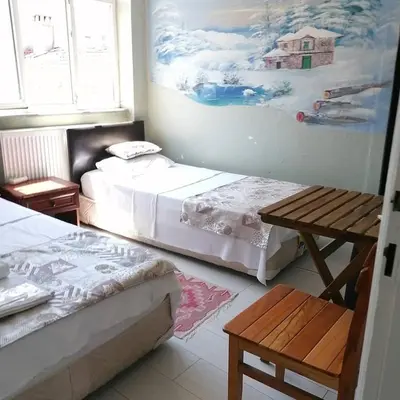 a room with two beds and a table and a painting at Hotel Mudanya in Mudanya