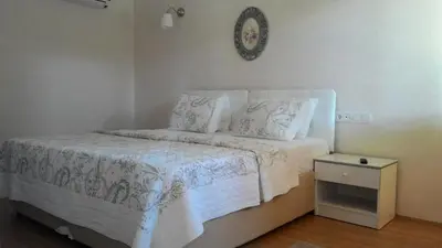 a bedroom with a white bed and a clock on the wall at Zumrut Bahce in Gokcedere
