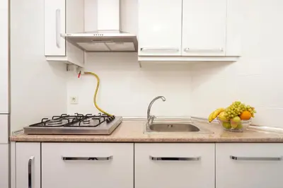 a kitchen with white cabinets and a sink and a bowl of fruit at Cozy Apartment Next to Taksim Square in Istanbul