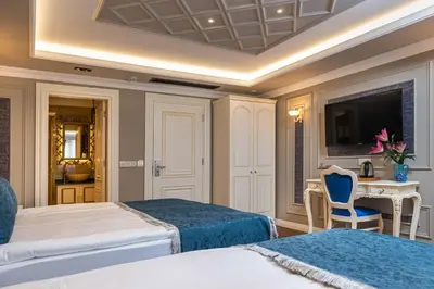 a bedroom with two beds and a table and a tv at Begonville Mansion Oldcity in Istanbul