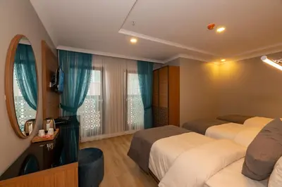 a hotel room with three beds and a television at New Emin Hotel in Istanbul
