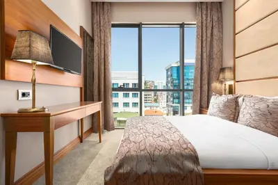 a hotel room with a bed and a desk with a large window at Days Hotel by Wyndham Istanbul Maltepe in Istanbul