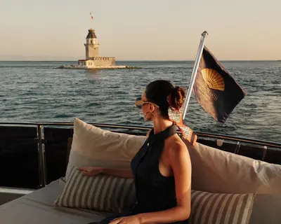 a woman sitting on a boat with a lighthouse at Mandarin Oriental Bosphorus, Istanbul in Istanbul