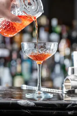 a person pouring a drink into a martini glass at Orientbank Hotel Istanbul, Autograph Collection in Istanbul