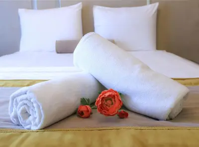 a white towel and two red roses on a bed at Burçman Hotel Vişne in Yıldırım