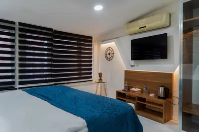 a bedroom with a bed with a blue blanket and a tv at The Havana Residence in Istanbul