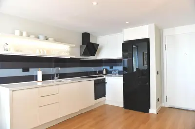 a kitchen with white cabinets and a black refrigerator at G Tower Furnished Apartment Rentals in Istanbul