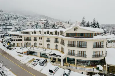 a large white building with cars parked in the snow at Motali Life Hotel in Masukiye