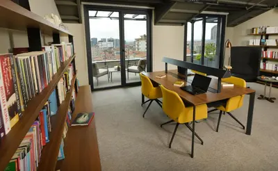 a library with a desk with a laptop and yellow chairs at Antwell Suites in Istanbul