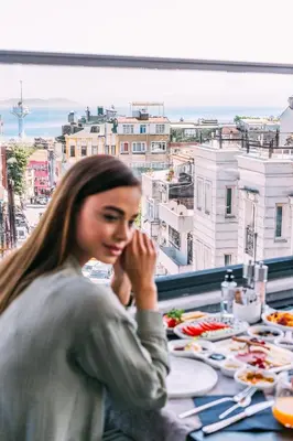 a woman sitting at a table with a view of a city at RW BOUTIQUE HOTEL in Istanbul