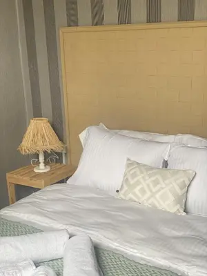 a bed with white sheets and a table with a lamp at Ikigai Hotel Villa Rıfat in Adalar