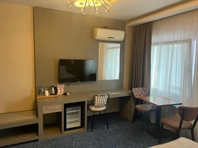 a hotel room with a desk with a television and a table at Acar Suite Hotel in Istanbul