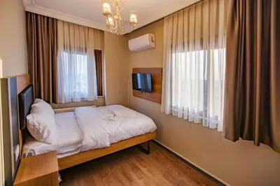 a bedroom with a bed and a tv and windows at Grand Balyan Hotel & Restaurant in Istanbul