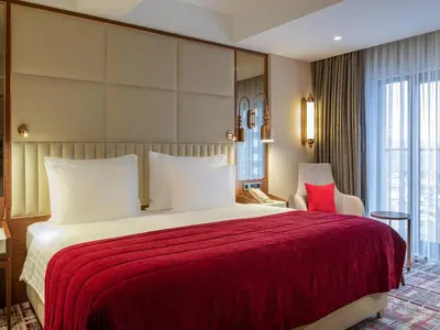 a hotel room with a large bed with a red blanket at Mövenpick Hotel Istanbul Asia Airport in Istanbul