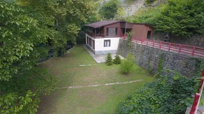 a house in the middle of a yard with a stone wall at Feel & Live Hotel Villas Restaurant Sapanca in Sakarya