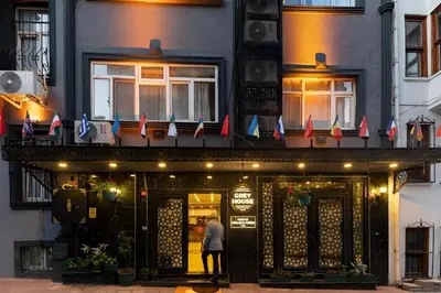 a man standing in front of a building with flags at Grey House Apartments & Suites Istanbul in Istanbul