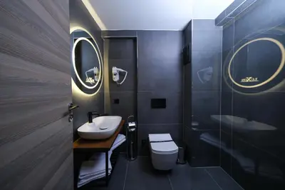 a bathroom with a sink and a toilet and two mirrors at Luxon Hotel Sakarya in Sakarya