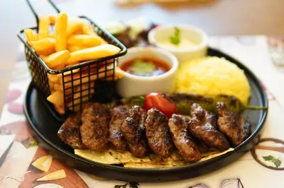 a plate of food with meat and french fries and sauce at King City Hotel Istanbul Ataturk Airport in Istanbul