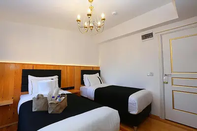 a hotel room with two beds and a chandelier at Taksim Istiklal Street Kamilbey Hotel in Istanbul