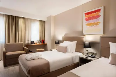 a hotel room with two beds and a chair at İzz Hotel Koşuyolu in Istanbul