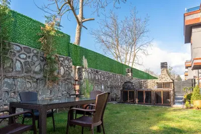 a stone wall with a table and chairs in a yard at Andalus Villas NO ALCOHOL ALLOWED with Heated Pool in Sapanca