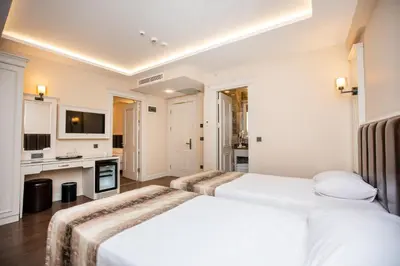 two beds in a white room with a tv at PRAG HOTEL in Istanbul
