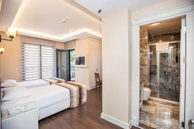 a bedroom with a large white bed and a bathroom at Opatija Hotel in Istanbul