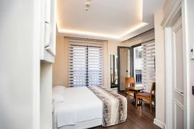 a bedroom with a white bed and a table and chairs at Opatija Hotel in Istanbul
