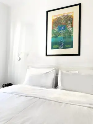 a bedroom with a white bed with a picture on the wall at Petek Pansiyon Fenerbahce Kadikoy in Istanbul