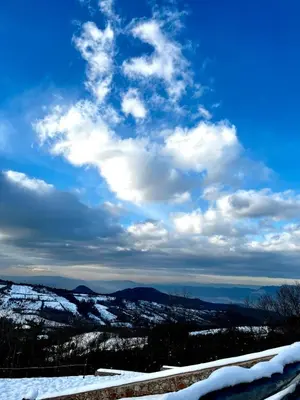 a blue sky with clouds and snow covered mountains at Masklavi in Kestel