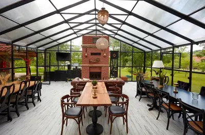 a greenhouse with tables and chairs and a fireplace at Dachas Cove Hotel in Agva
