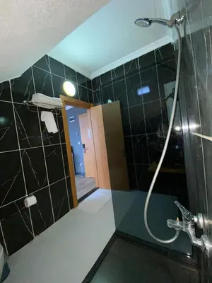 a bathroom with a shower with black tiles at 216 Hill Suites in Istanbul