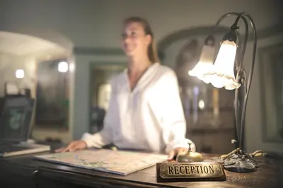 a woman sitting at a desk next to a lamp at Princely Suites Nişantaşı in Istanbul