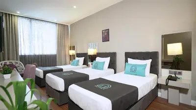 a hotel room with three beds with blue pillows at Homey AirPort Hotel in Arnavutköy