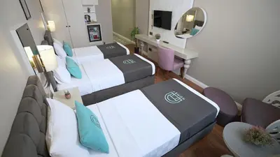 a hotel room with two beds and a desk at Homey AirPort Hotel in Arnavutköy