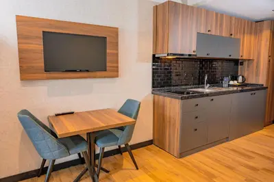 a kitchen with a table and a sink and a tv at Görükle Alpaş Yaşam Hotel in Bursa