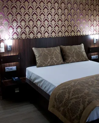 a bedroom with a bed and a wall covered in wallpaper at Istanbul Central Hotel in Istanbul