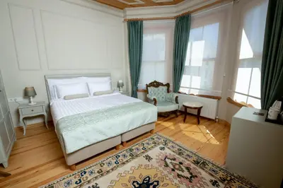 a bedroom with a bed and a chair and windows at İkiz Konak Boutique Hotel in Istanbul