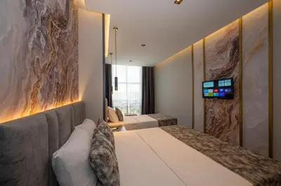 a bedroom with two beds and a television on a wall at World Class Hotel - Istanbul Airport in Arnavutköy